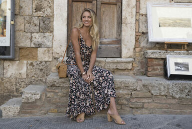 A blonde woman sitting on the steps of an old building.