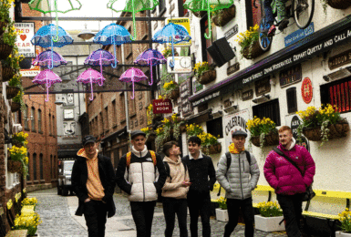 A group of cairde walking down a cobblestone street.