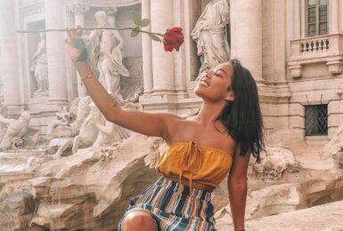 A woman holding a rose at the Trevi Fountain.