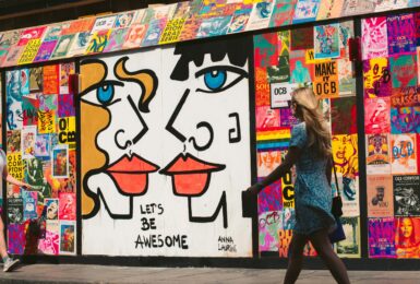 A woman walking past a mural depicting a couple in Great Britain.