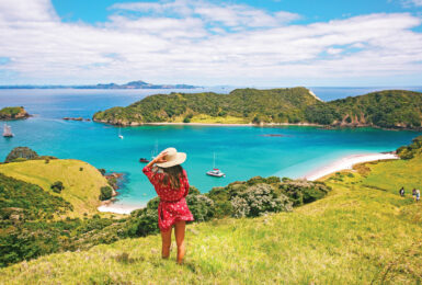 A woman is standing on a hill overlooking the ocean in one of the happiest countries.