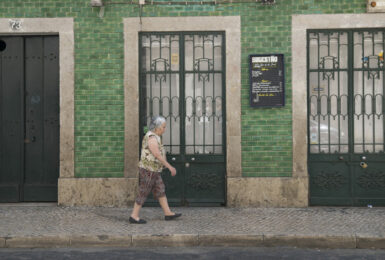 A woman travelling in front of a building.