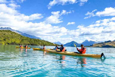 A group of people paddling in kayaks on a lake.