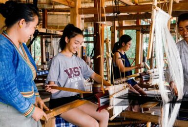 In celebration of International Women's Day, a diverse group of women come together to skillfully work on a weaving loom.