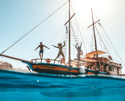 Friends jumping off boat into water having fun in Europe