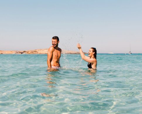 Image of a man and woman in the sea, playfully splashing about