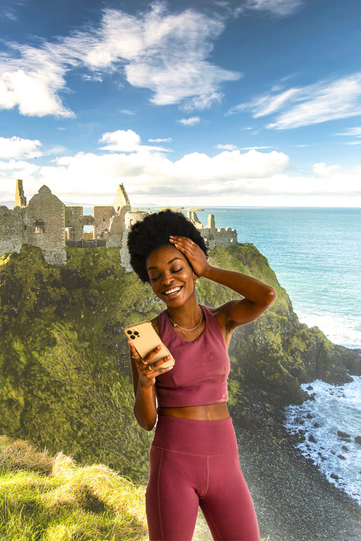 Young woman with Dunluce Castle in Northern Ireland as the background.
