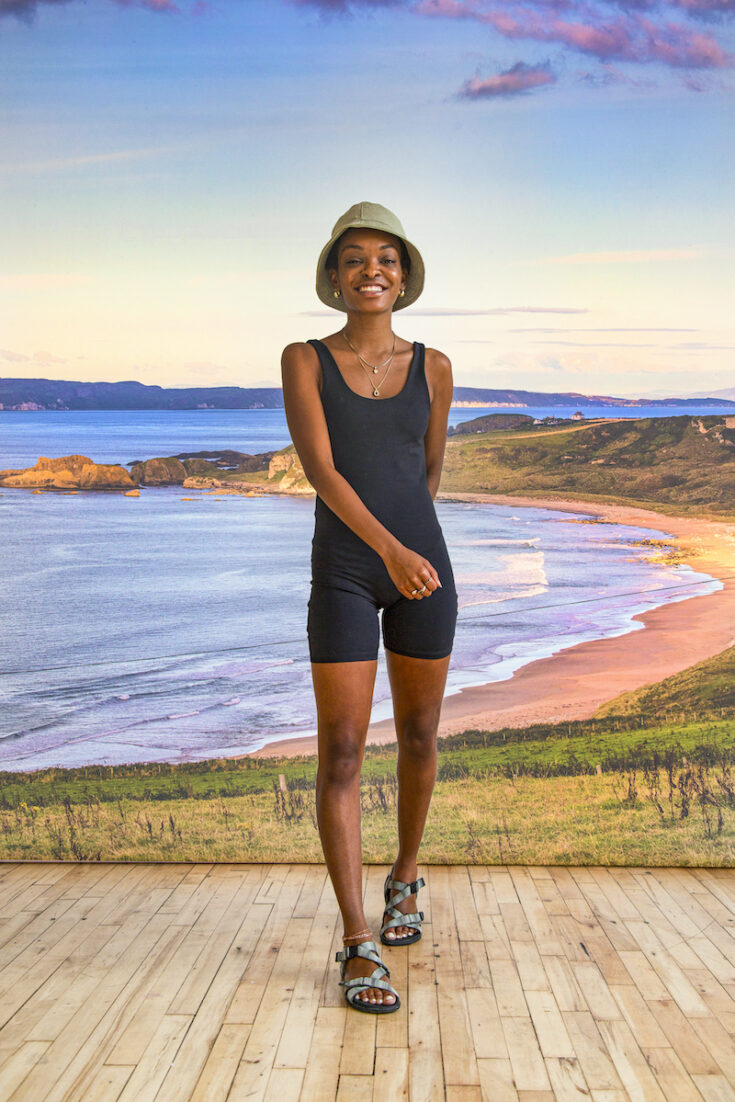 Young woman standing with coastline in Northern Ireland as the background.