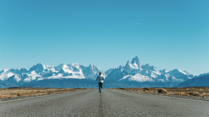 Man running on the road with Patagonia Mountains in the background.