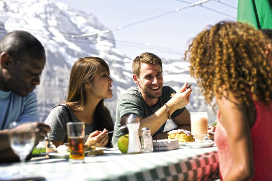 A group of people sitting at a table with the Swiss Alps in the background.