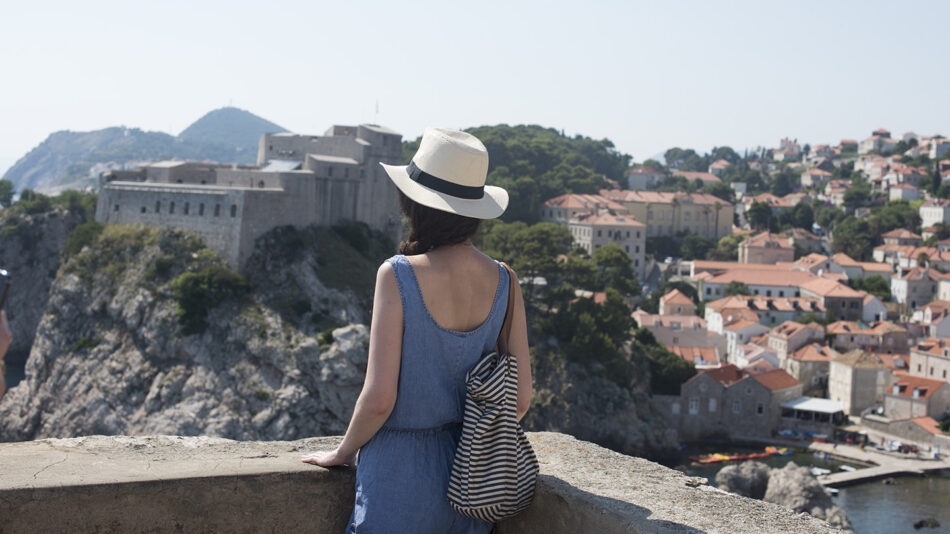 A woman in a hat is enjoying some self-care while looking out over the city of Dubrovnik.