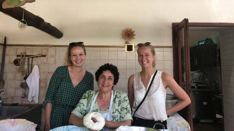 Three women posing for a photo in a kitchen.
