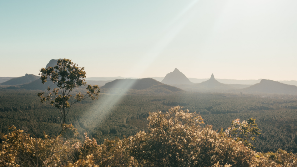 Queensland, one of the best places to visit in Australia, boasts a stunning landscape with the sun shining over the mountains.