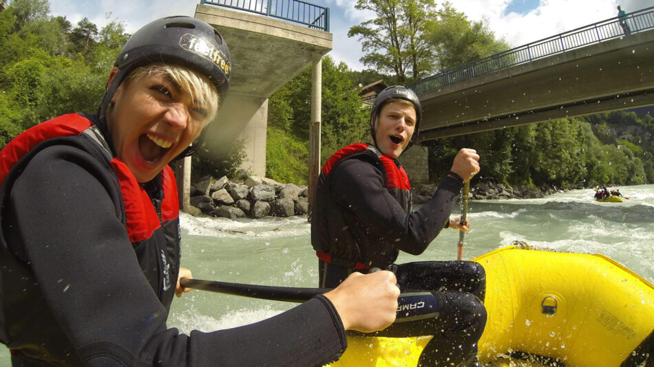 Experience Europe's best adventure activities while two people navigate down a picturesque river in a vibrant yellow raft.
