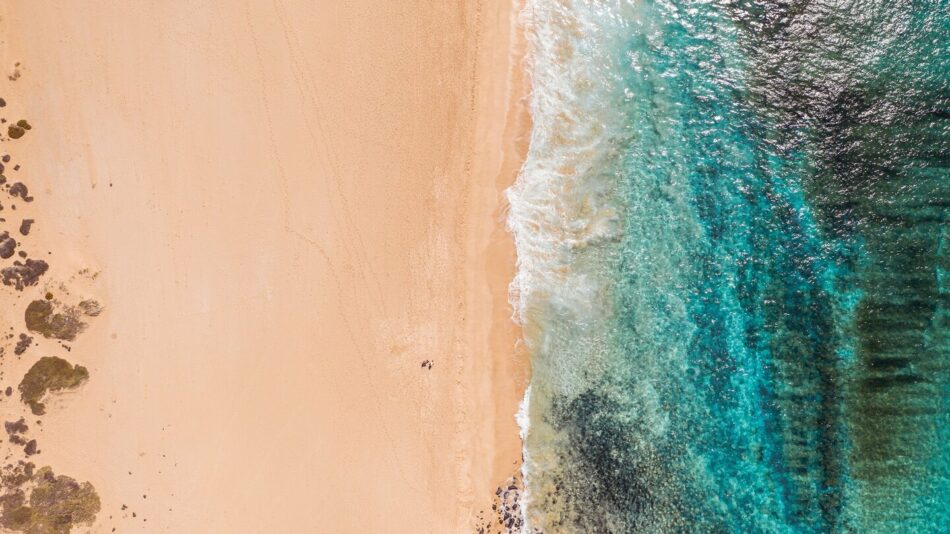 An aerial view of a sunny beach and ocean.