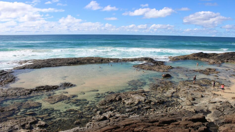 A rocky beach with a small pool of water.