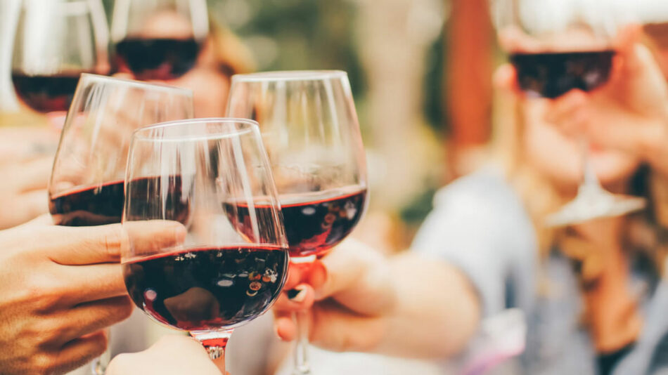 A group of people on a food tour toasting red wine glasses.