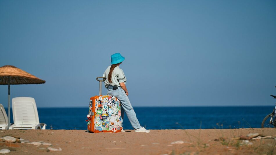 young traveler on the beach sitting on luggage