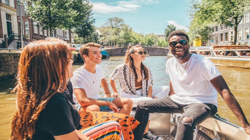 A group of people on a boat exploring the canals of Amsterdam, following the latest travel trends.