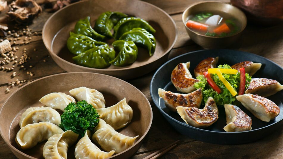 Three bowls of dumplings on a wooden table, fulfilling a travel bucket list item.