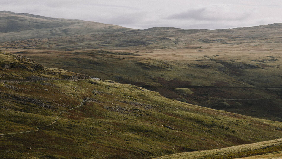 A man riding a horse down a hillside, showcasing the adventurous outdoor activities of Great Britain.