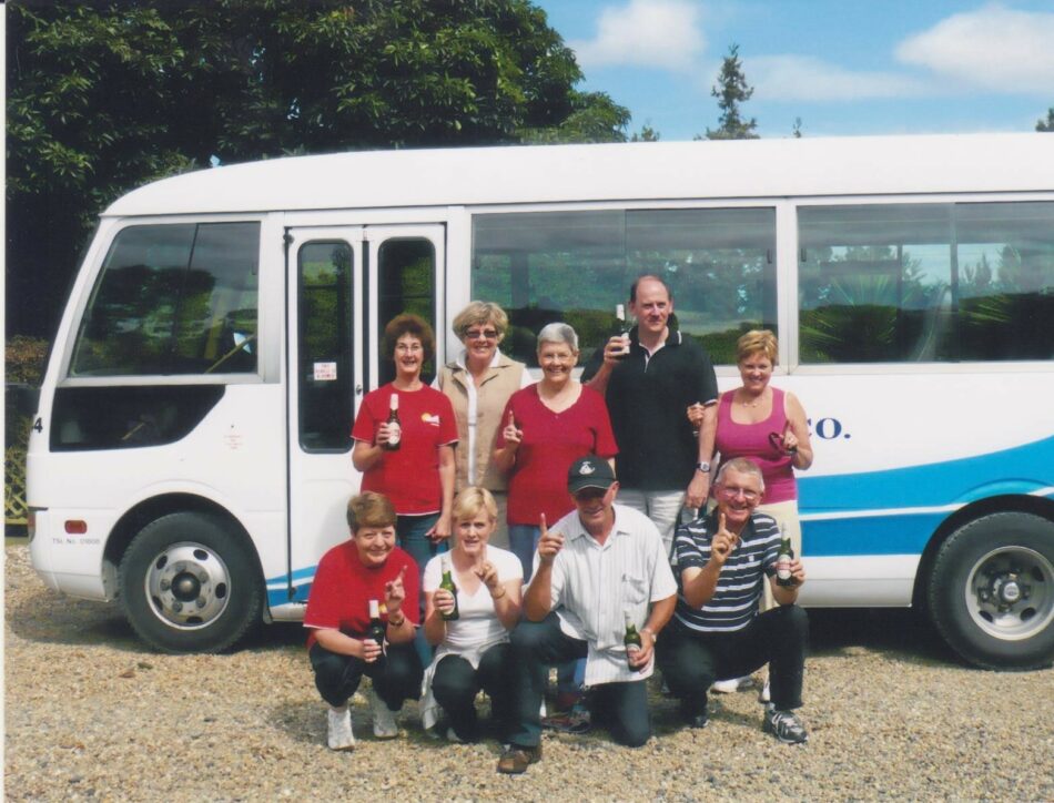 A Contiki reunion group posing in front of a bus.