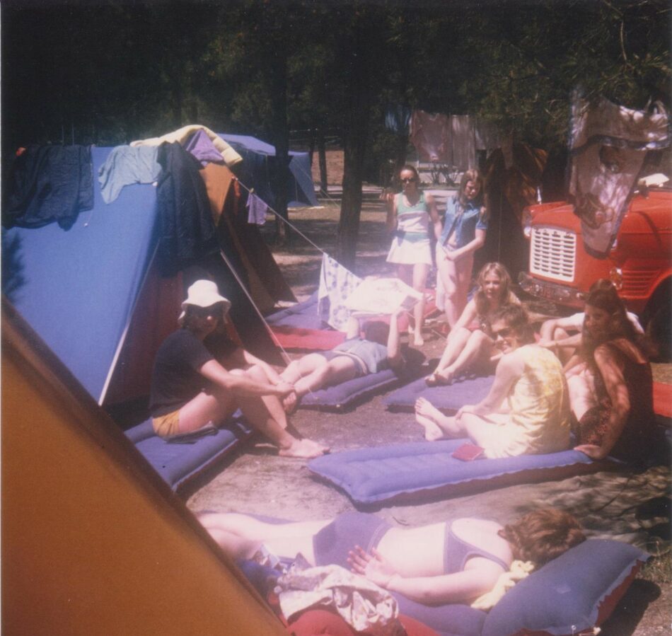 A Contiki reunion, with a group of people laying on the ground in front of a tent.