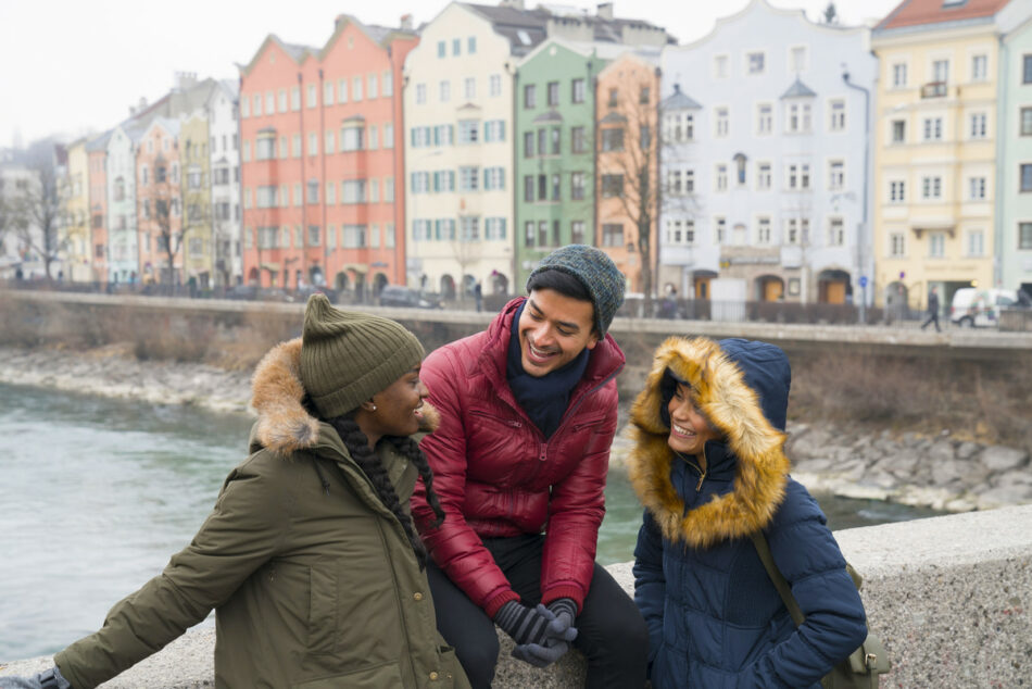 A group of people travelling to Europe for the first time standing on a bridge near a river.