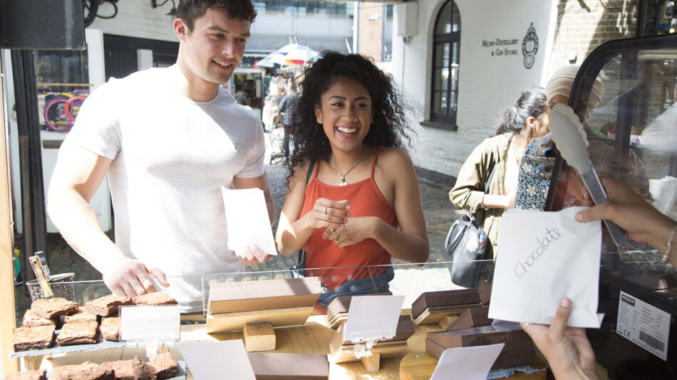 A group of Londoners standing in front of a food stand.