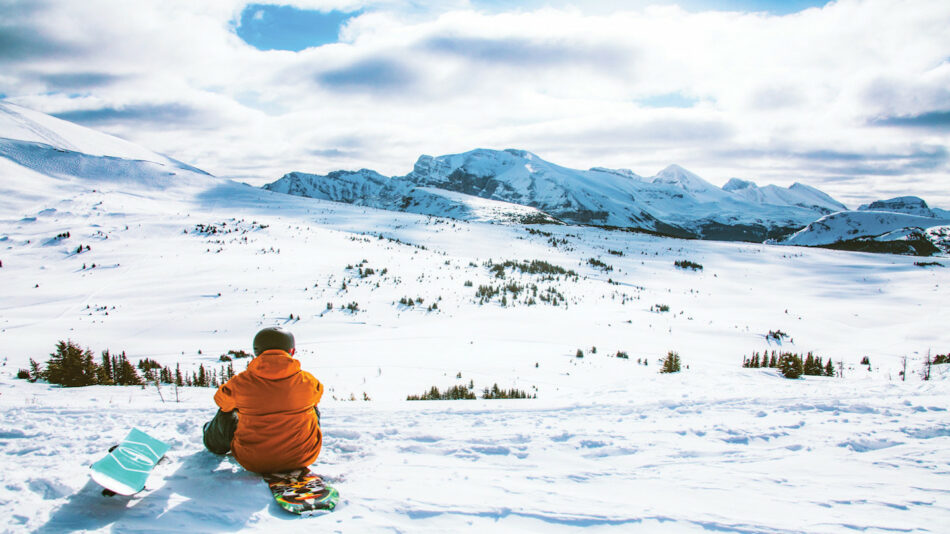 An instagrammable person sitting on a snow covered mountain.