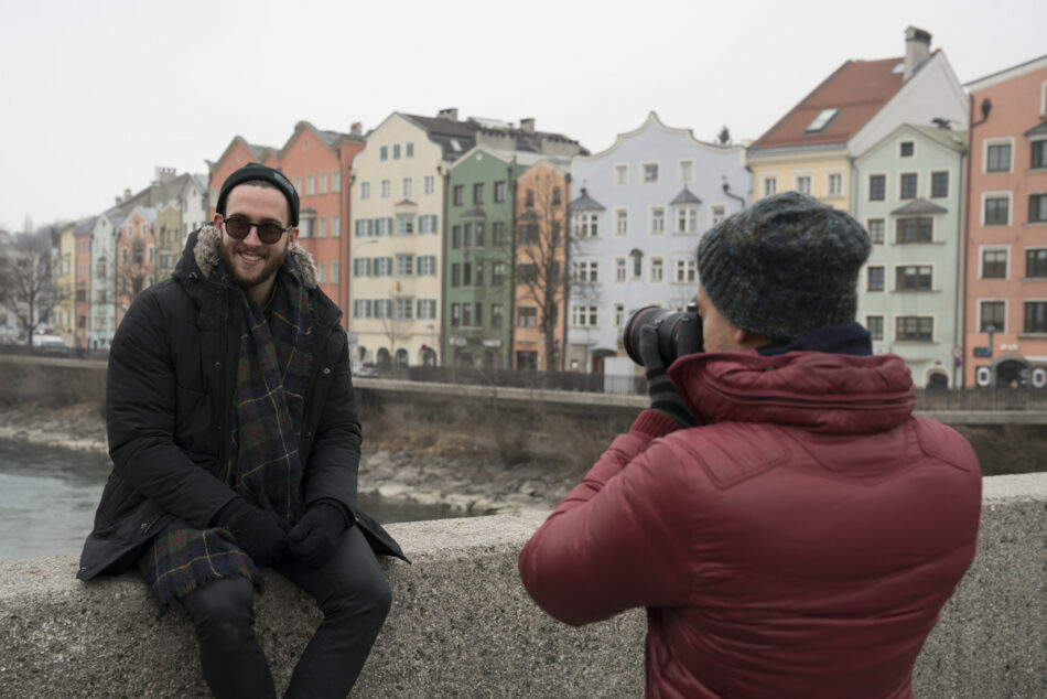 A man is capturing an LGBTQ traveler on a bridge.