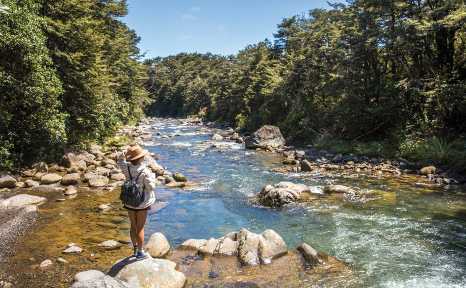 A woman enjoying outdoor activities near a river in New Zealand.