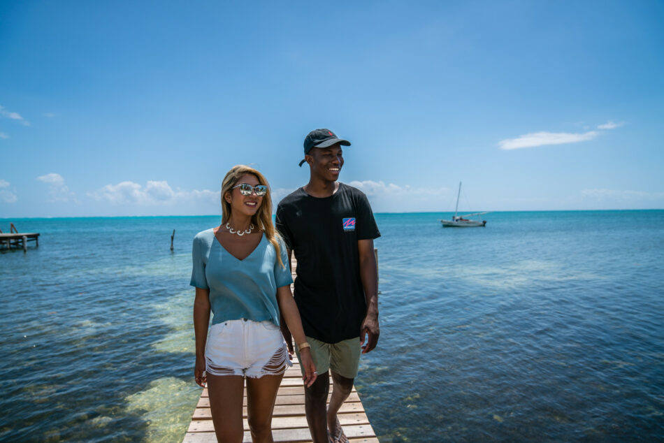 A couple experiencing post travel blues while walking on a dock near the ocean.