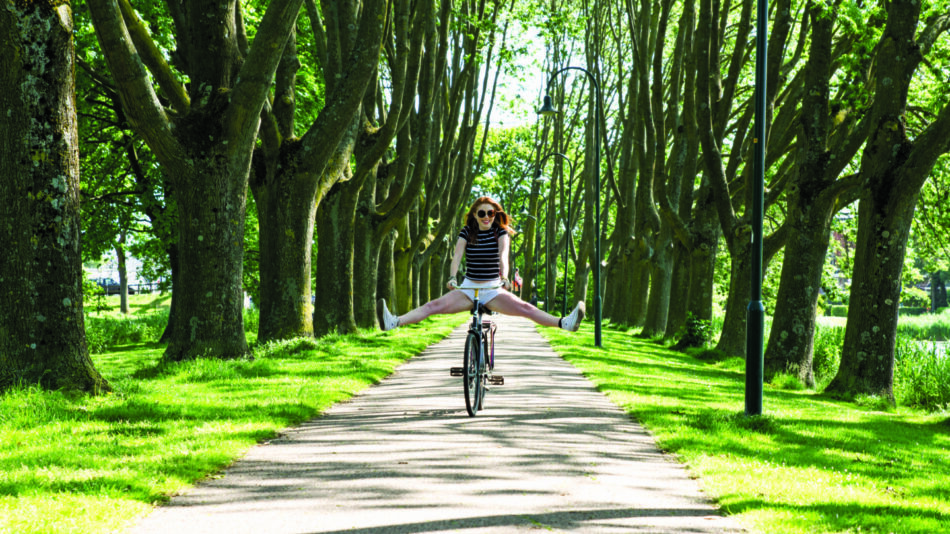 A woman enjoys a solitary bike ride along a scenic path.