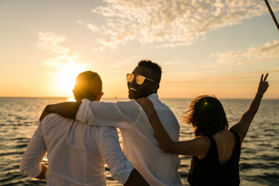 A group of LGBTQ friends on a boat at sunset.