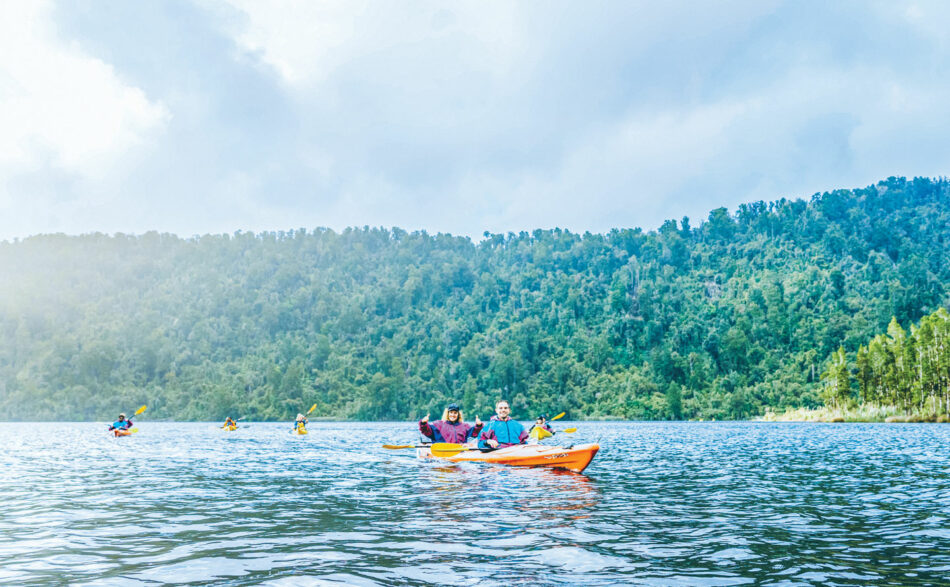 A group of people paddling in a kayak on a lake.