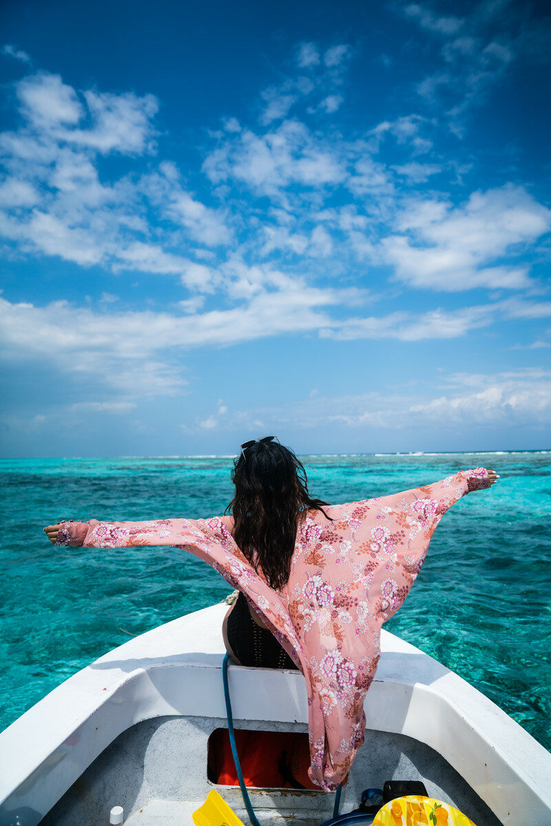 A woman on a boat experiencing post-travel blues with her arms outstretched.