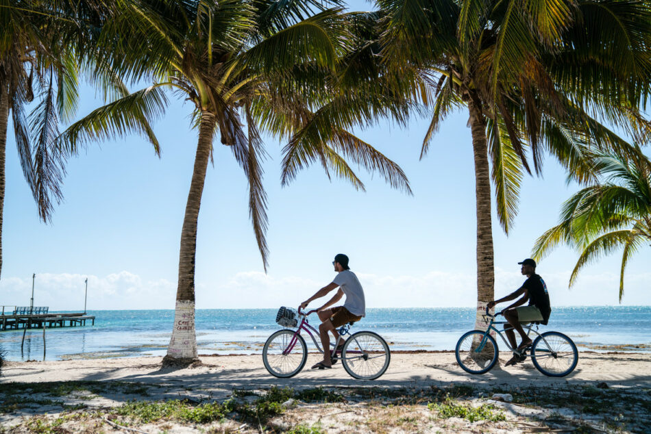 Two individuals exploring the vibrant gay travel scene while biking on the beach.