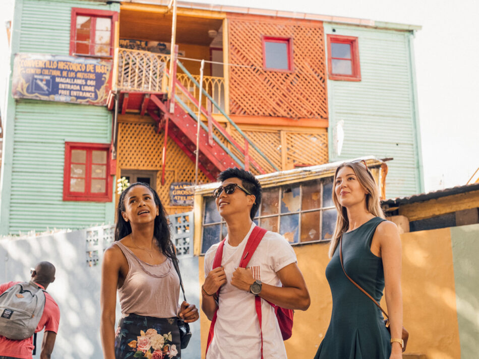 People standing outside a beachy building with Spanish writing on the walls