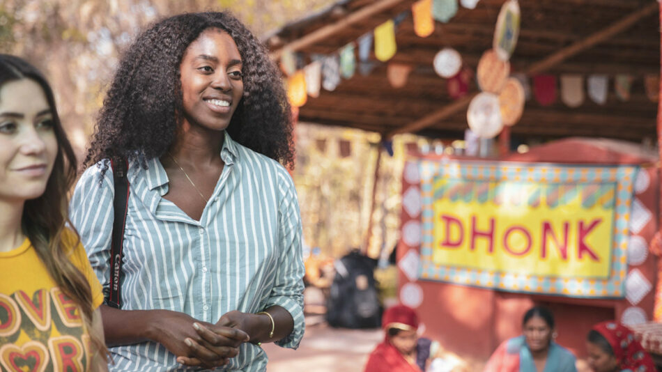 Two women standing in front of a dhoonk sign promoting sustainability goals.