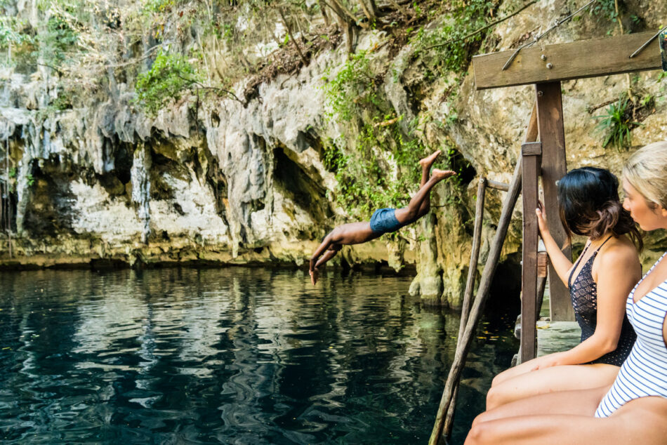 A group of people enjoying a summer fling by jumping into the water from a dock.