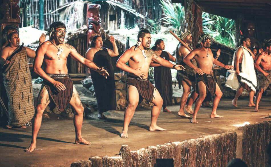 A group of people performing a dance in a hut.