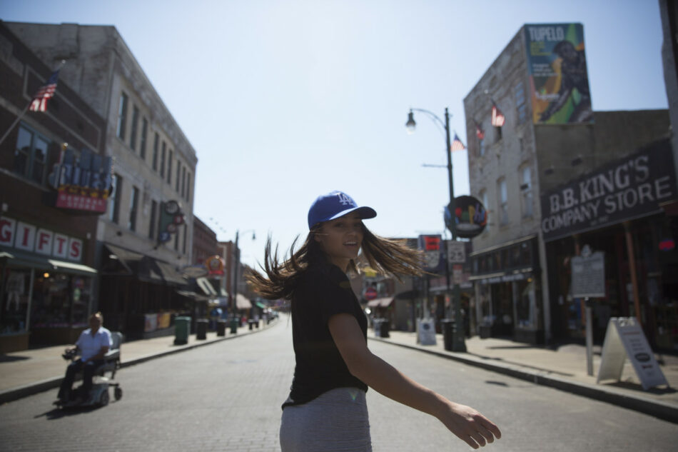 A woman is exploring the ways travel has changed while walking down a street.