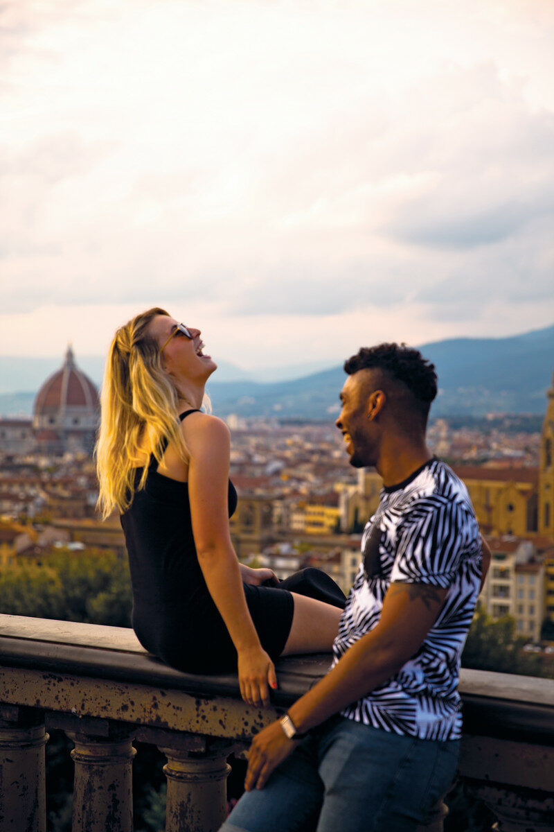 A couple enjoying a summer fling on a balcony overlooking the city of Florence.