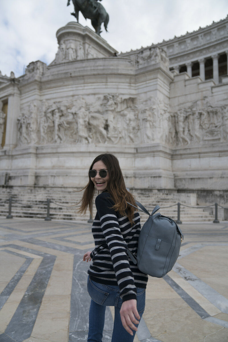 A woman with a backpack in front of a statue during her winter trip in Europe with Contiki.