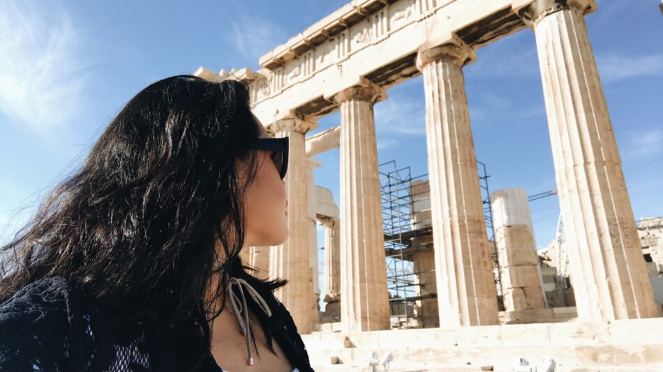 A woman exploring the Parthenon in Acropolis as part of her Greece travel guide.