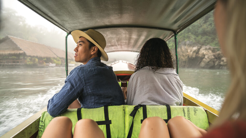 Two people sitting on the back of a boat in thailand.