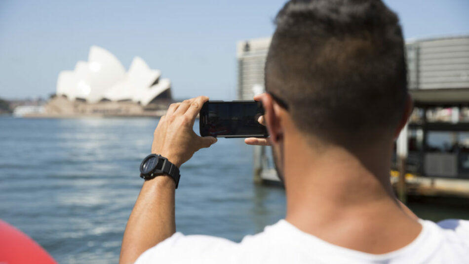 A man experiences reverse culture shock while photographing the Sydney Opera House with his phone.