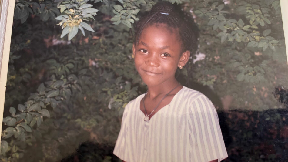 A young girl standing in front of a tree.