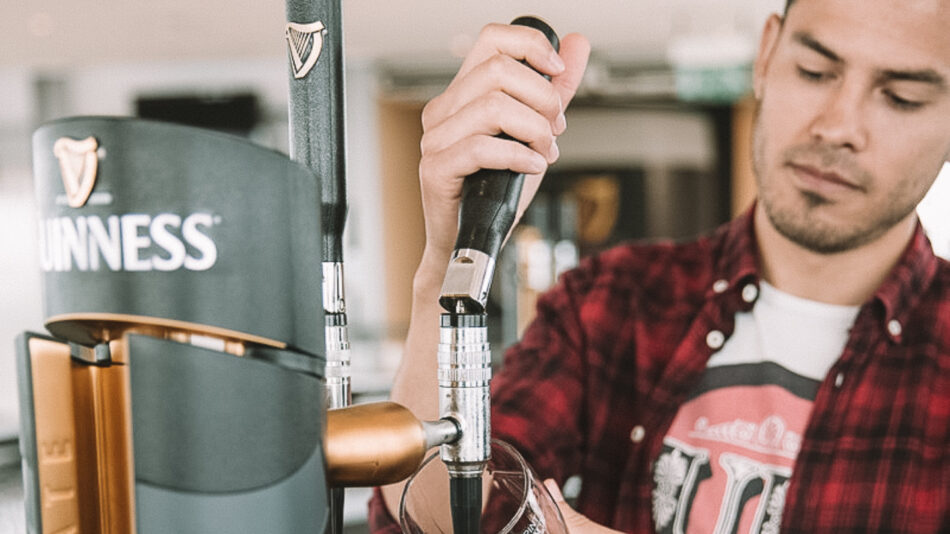 A man is pouring guinness beer into a glass.